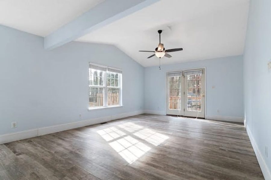 Empty living room with vaulted ceiling, refinished hardwood floors, ceiling fan
