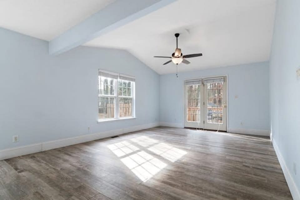 Empty living room with vaulted ceiling, refinished hardwood floors, ceiling fan