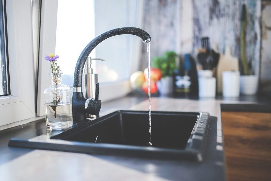 Modern kitchen sink with matte black faucet and marble surround