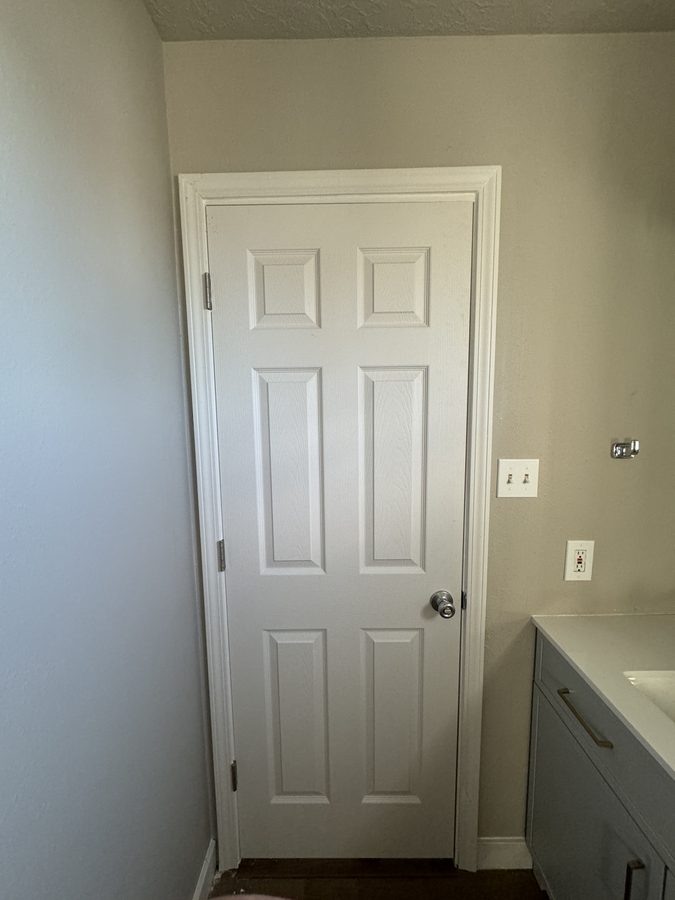 Clean six-panel white interior door installed against white wall