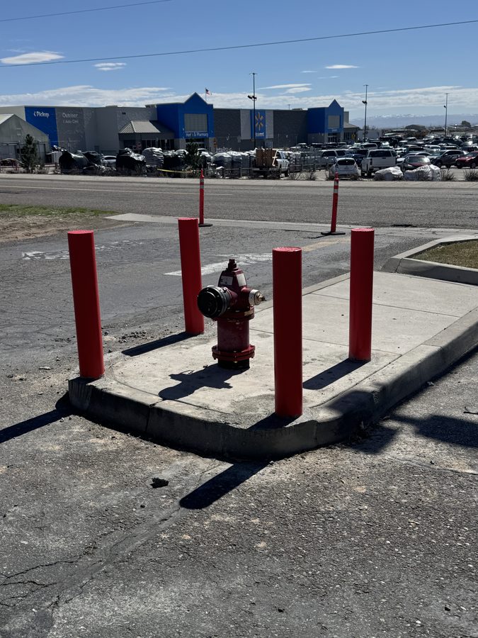 Red protective bollards installed in a commercial parking lot