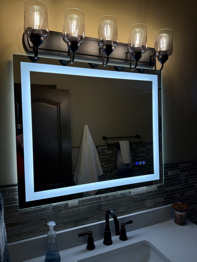 Lit-frame mirror with Edison bulb sconces and dark vanity